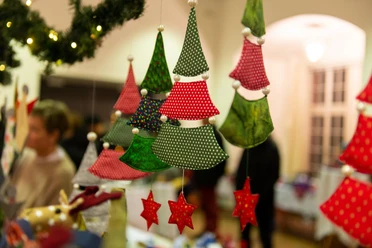 Weihnachtsmarkt Ein Weihnachtsmarkt mit handgemachtem Dekor aus bunten Stoffen und Sternen. Die festliche, warme Atmosphäre lädt zur kreativen Entdeckung ein, während Menschen im Hintergrund vorbeischlendern.
