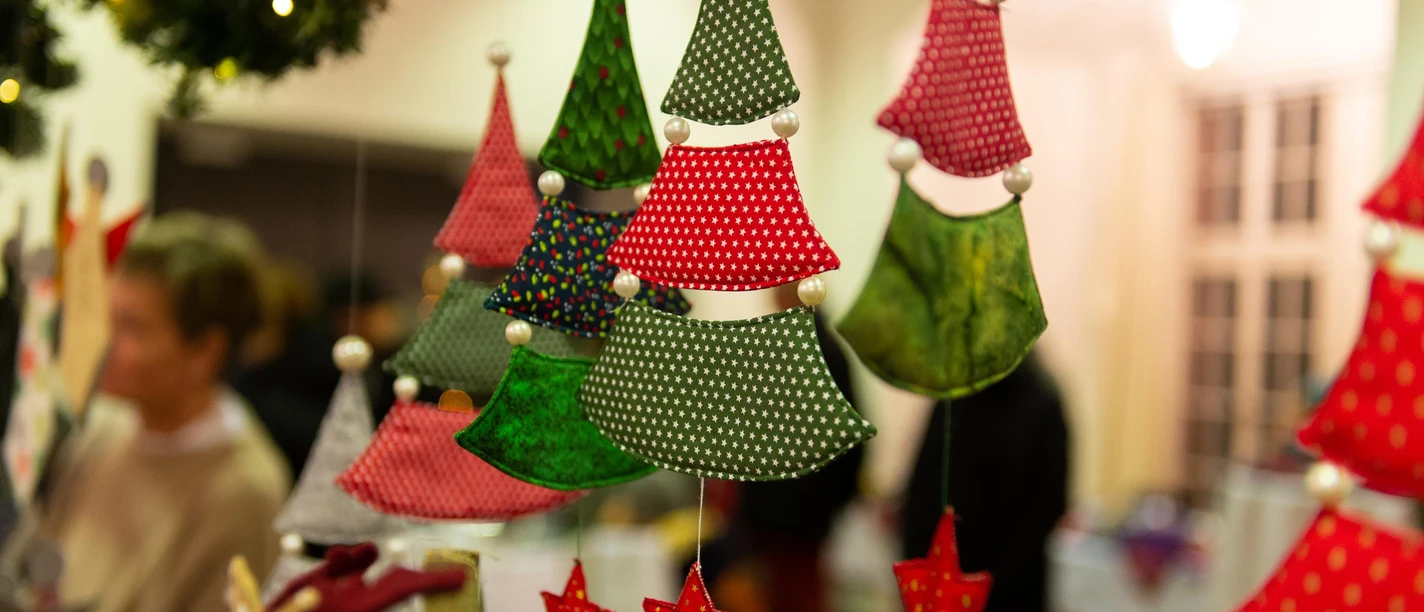 Weihnachtsmarkt Ein Weihnachtsmarkt mit handgemachtem Dekor aus bunten Stoffen und Sternen. Die festliche, warme Atmosphäre lädt zur kreativen Entdeckung ein, während Menschen im Hintergrund vorbeischlendern.