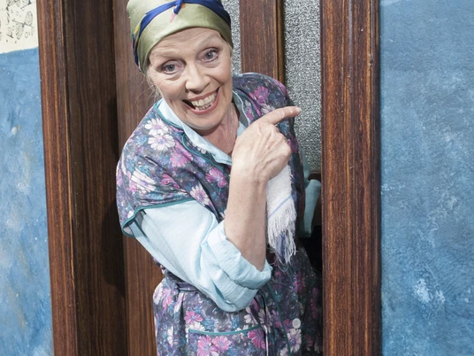 Tratsch op de Trepp.jpg Das Bild zeigt eine Schauspielerin, die gerade aus der Tür schaut