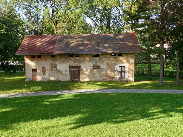 Old stone house with red roof in a sunny park.