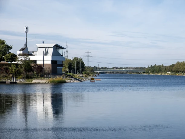 Fühlinger See Am Ufer des Fühlinger Sees in Köln ragt ein modernes Gebäude hervor, umgeben von Wasser und Bäumen.