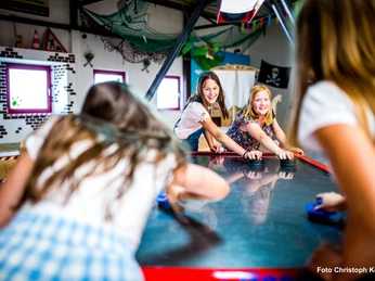 Airhockey im Happylino Kinder spielen fröhlich Airhockey in der bunten Happylino Indoor-Spielhalle mit Piratendekoration.