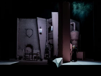 Auf einer Bühne sind dramatisch beleuchtete Theaterkulissen mit einem geheimnisvollen Charakter zu sehen.