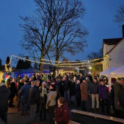 Besucher auf dem Weihnachtsmarkt von Elstertrebnitz in festlicher Abendstimmung.