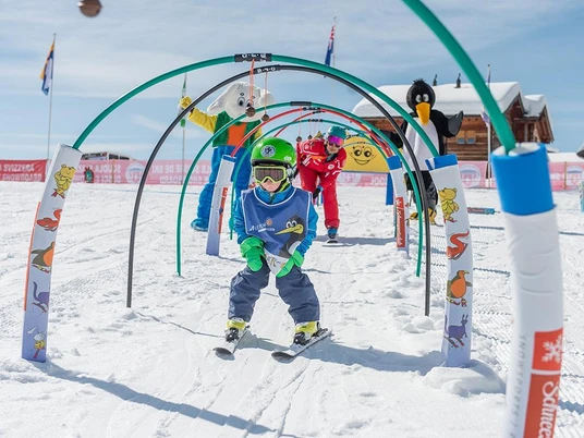 Les enfants apprennent à skier à Riederalp Ski Schnupperkurs Riederalp mit Kind im Kinderland der Schweizer Skischule unter Anleitung und MaskottchenSki taster course Riederalp with child in the children's area of the Swiss Ski School with instruction and mascotCours d'initiation au ski à Riederalp avec enfant au Kinderland de l'École Suisse de Ski sous la conduite d'un guide et d'une mascotte