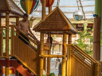AQUALAND - wellness and aquapark Bambuskonstruktion mit Wasserspielen und leuchtend farbigen Rutschen im Freizeitbad.Bamboo construction with water features and brightly colored slides in the leisure pool.