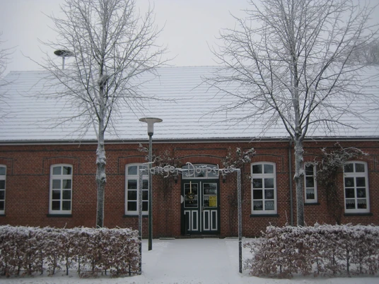 Dörpshus Tange im Winter Backsteingebäude mit weißen Fenstern im Winter, verschneite Bäume und Hecke davor.Brick building with white windows in winter, snow-covered trees and a hedge in front of it.Murstensbygning med hvide vinduer om vinteren, snedækkede træer og en hæk foran.Bakstenen gebouw met witte ramen in de winter, besneeuwde bomen en een heg ervoor.