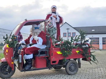 Weihnachtsmarkt Elstertrebnitz - Weihnachten in der Region Leipzig Der Weihnachtsmann fährt ein rotes Dreirad, geschmückt mit Nadelzweigen und Zuckerstangen.