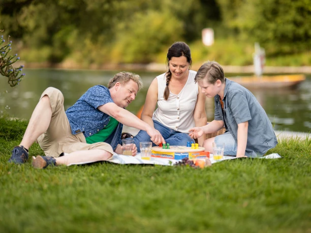 Campingplatz Kassel Eine Familie spielt ein Brettspiel auf der Wiese während ihres Aufenthalts auf dem Kasseler Campingplatz.