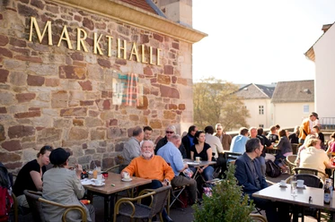 Markthalle in Kassel im Sommer Vor der Markthalle sitzen Personen auf der Terrasse im Sommer.