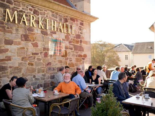 Markthalle in Kassel im Sommer Vor der Markthalle sitzen Personen auf der Terrasse im Sommer.