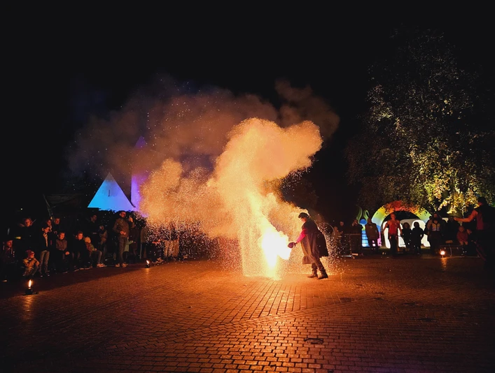 Feuershow der Rasteder Lichternacht.jpg Feuershow in der Nacht mit Funkenregen, umgeben von Zuschauern und bunt beleuchteten Zelten.