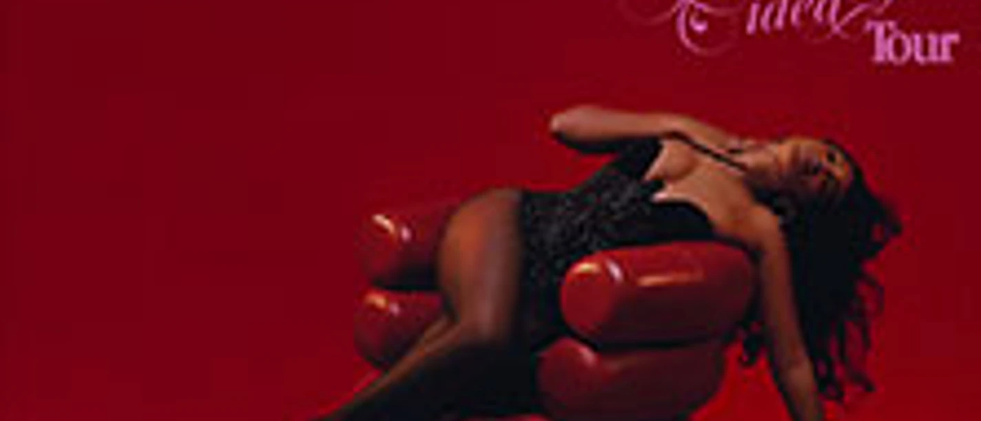 Künstlerinnensitz auf rotem Stuhl vor rotem Hintergrund mit "Amber Mark" Schriftzug.