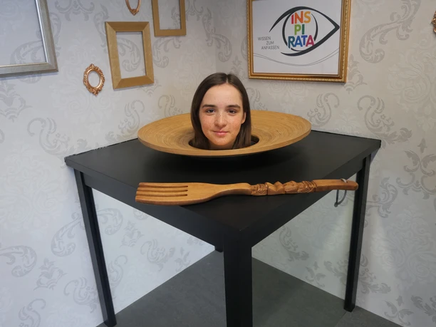 Die INSPIRATA - Optische Täuschung Der Kopf einer jungen Frau liegt in einer optischen Täuschung in der INSPIRATA scheinbar auf einem Teller auf einem Tisch