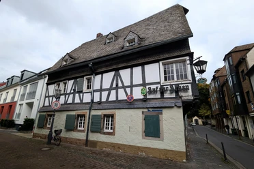 ©Bastian Ulrich - Haus auf der Arken 3 Das Bild zeigt ein traditionelles Fachwerkhaus mit neun Fenstern und einem langen Schornstein.