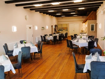 Innenansicht Saal Patchwork Köthel.jpg Innenansicht Saal Patchwork Köthel mit Tischen, Stühlen, Holzfußboden und Deckenbalken.