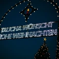 Weihnachtsmarkt Taucha - Weihnachten in der Region Leipzig Leuchtendes Weihnachtsschild in Taucha bei Nacht, umrahmt von bunten Lichtern und einem Tannenbaum.
