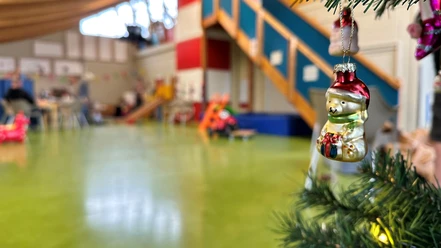 Kinderspielhaus_22-12_Weihnachten8_Wesler.jpg Weihnachtlich geschmückter Raum im Kinderspielhaus mit glänzendem Baumschmuck und Spielgeräten