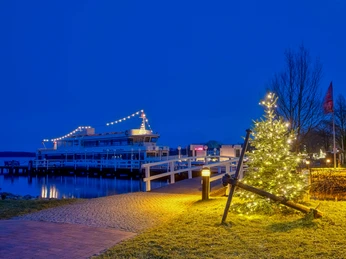 weisse_flotte_lichterwochen Beleuchtetes Fahrgastschiff an winterlichem Steg mit geschmücktem Weihnachtsbaum bei Nachtstimmung