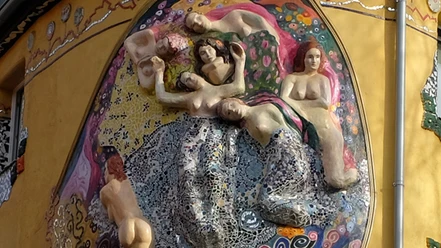 Liebe, Lust und Fisimatenten Eine detailreiche Mosaikskulptur an einer Gebäudewand zeigt mehrere ruhende Figuren.