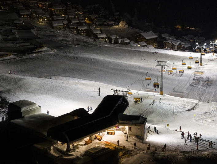 "Panoramic view of the slopes during night skiing in the Aletsch Arena Night skiing Bettmeralp Riederalp shows illuminated pistes, chairlifts and skiers in the winter paradise of the Aletsch Arena under a clear starry sky