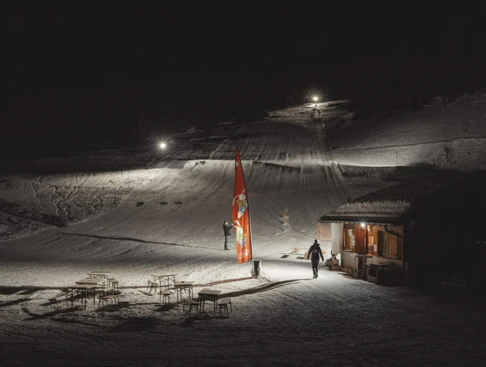 Night skiing at the Fieschertal family ski lift Night skiing Fieschertal shows the illuminated valley station of the Blaetz family ski lift with skiers and a cozy hut atmosphere in the Aletsch Arena