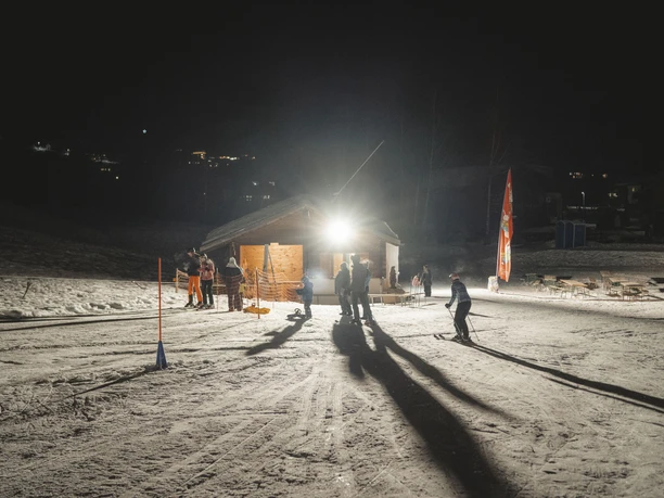 Ski lift and hut lights for night skiing in the Fieschertal valley Night skiing Fieschertal shows the illuminated Blaetz ski lift with skiers and visitors in the warm light of the Aletsch Arena at night