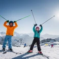 Kinder geniessen das Skifahren in der Aletsch Arena Beim Schgi fer frii Aletsch Arena fahren zwei Kinder lachend Ski auf der sonnigen Piste mit Blick auf die verschneiten Walliser AlpenAt the Schgi fer frii Aletsch Arena, two children ski with a smile on the sunny slope with a view of the snow-covered Valais AlpsAu Schgi fer frii Aletsch Arena, deux enfants skient en riant sur la piste ensoleillée avec vue sur les Alpes valaisannes enneigées.