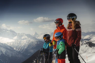 Familie geniesst Skitag mit Panorama in der Aletsch Arena Beim Familien Skipass Aletsch Arena geniesst eine Familie den Blick auf die verschneiten Walliser Alpen während einer Skitour bei sonnigem Wetter