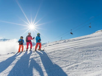 Sunny day of skiing with the family in the Aletsch Arena Beim Familien Skipass Aletsch Arena fahren Eltern mit ihren Kindern auf einer sonnigen Skipiste über der Fiescheralp mit klarer Sicht auf die AlpenWith the Aletsch Arena family ski pass, parents ski with their children on a sunny ski slope above the Fiescheralp with a clear view of the AlpsAvec le forfait de ski familial Aletsch Arena, les parents et leurs enfants skient sur une piste ensoleillée au-dessus de Fiescheralp avec une vue dégagée sur les Alpes.