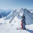 Les skieurs apprécient la vue sur l'Aletsch Arena Beim Wahltages Skipass Aletsch Arena stehen zwei Skifahrer an einem Aussichtspunkt mit Blick auf die schneebedeckten Gipfel der Walliser AlpenTwo skiers stand at a vantage point with a view of the snow-covered peaks of the Valais Alps during the Aletsch Arena ski pass voting dayLors de la journée de choix du forfait de ski Aletsch Arena, deux skieurs se tiennent à un point de vue avec vue sur les sommets enneigés des Alpes valaisannes.