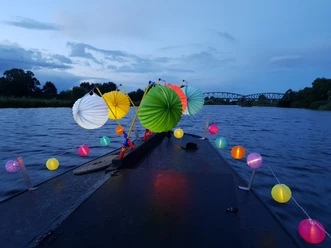 Lampionfahrt auf der Hamme Colorfully illuminated lanterns on a boat at dusk on the Hamme with a bridge in the background.