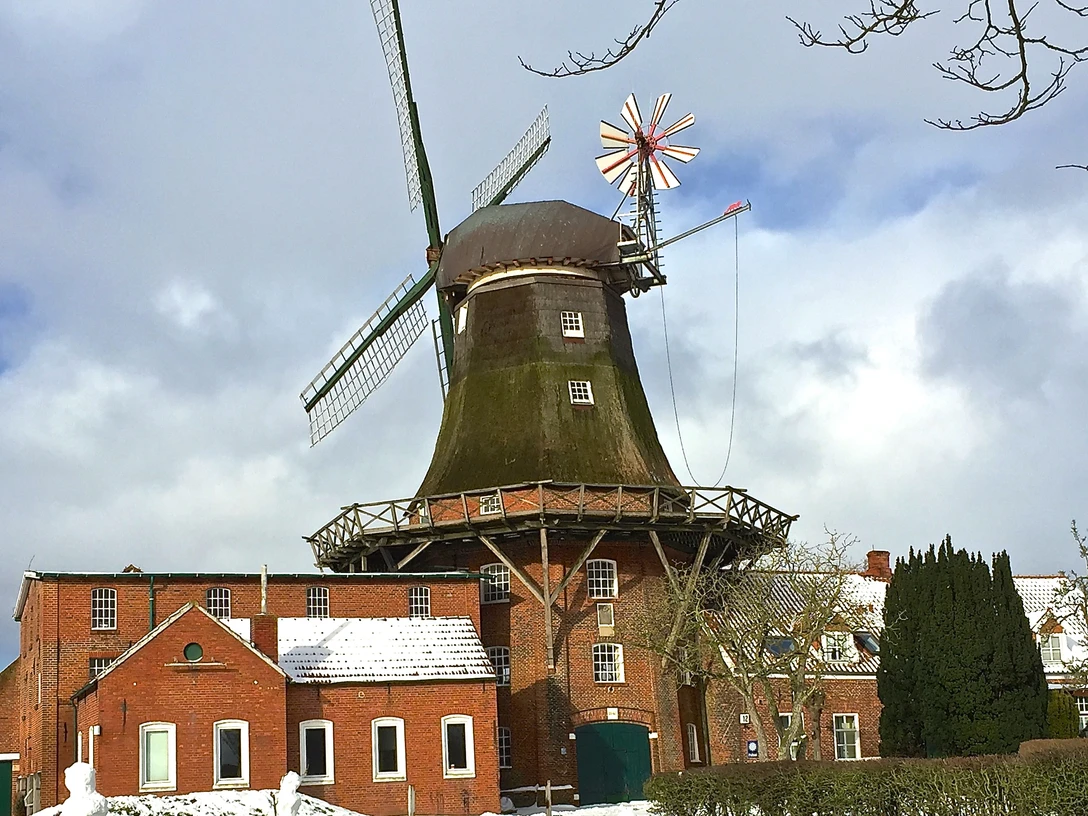 Mühle Pewsum im Winter Zu sehen ist die Mühle Pewsum im Winter, es liegt ein bisschen Schnee, im Vordergrund steht ein altes Fahrrad als Deko.You can see the Pewsum mill in winter, there is a bit of snow, in the foreground is an old bicycle as decoration.Man kan se Pewsum-møllen om vinteren, der er lidt sne, og i forgrunden står en gammel cykel som dekoration.Je ziet de Pewsum molen in de winter, er ligt een beetje sneeuw, op de voorgrond staat een oude fiets als decoratie.