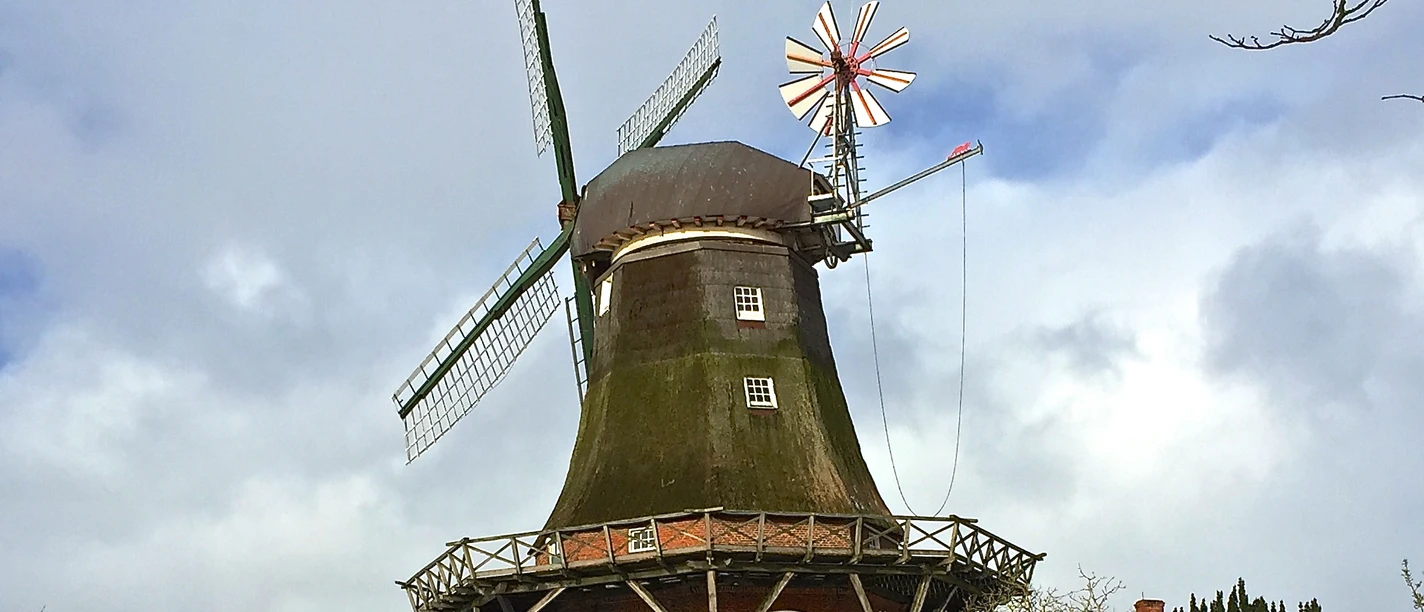 Mühle Pewsum im Winter Zu sehen ist die Mühle Pewsum im Winter, es liegt ein bisschen Schnee, im Vordergrund steht ein altes Fahrrad als Deko.
