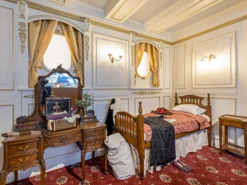 Passagierzimmer - Titanic: Eine Immersive Reise Foto eines nachgebauten Passagierzimmers auf der Titanic mit Schminktisch, Bett und Nachttisch in der Ausstellung "Titanic: Eine Immersive Reise"