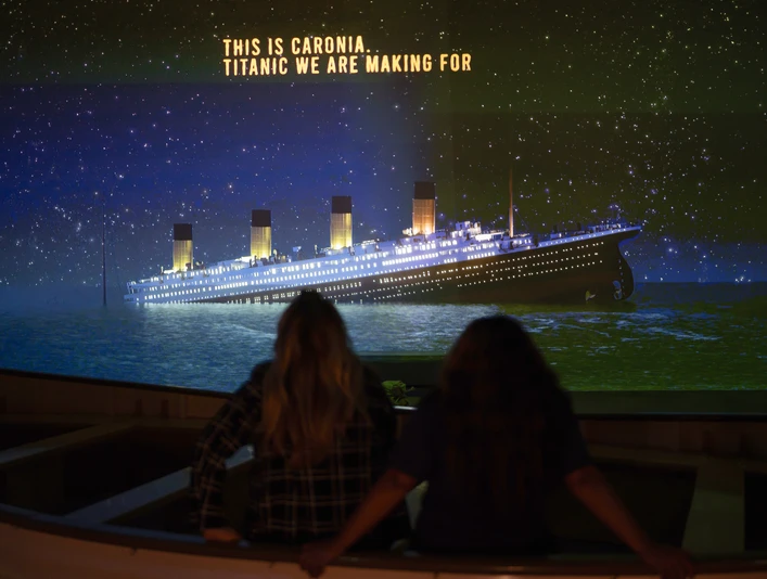Rettungsboot - Titanic: Eine Immersive Reise Zwei Frauen sitzen in einem Rettungsboot und sehen eine Projektion der sinkenden Titanic an in er Ausstellung "Titanic: Eine Immersive Reise"Two women sit in a lifeboat and watch a projection of the sinking Titanic in the exhibition "Titanic: An Immersive Journey"Dvě ženy sedí v záchranném člunu a sledují projekci potápějícího se Titaniku na výstavě "Titanic: An Immersive Journey".Dwie kobiety siedzą w szalupie ratunkowej i oglądają projekcję tonącego Titanica na wystawie "Titanic: An Immersive Journey".Twee vrouwen zitten in een reddingsboot en kijken naar een projectie van de zinkende Titanic in de tentoonstelling "Titanic: An Immersive Journey".Due donne siedono in una scialuppa di salvataggio e guardano una proiezione del Titanic che affonda nella mostra "Titanic: An Immersive Journey".
