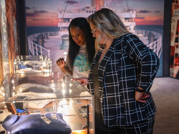 Two women look at exhibits from the time of the Titanic in the exhibition "Titanic: An Immersive Journey"
