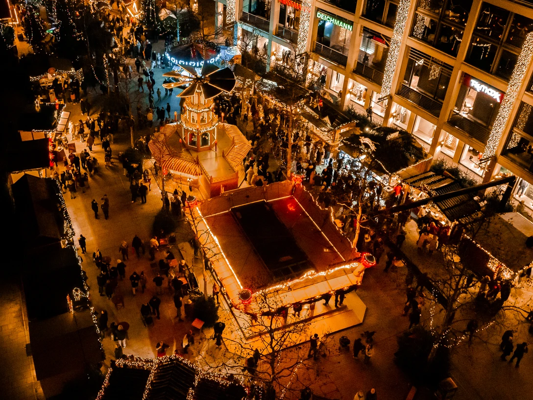 Luftaufnahme Wolfsburger Weihnachtsmarkt Blick von oben auf festlich beleuchteten Weihnachtsmarkt Menschen zwischen Buden.View from above of festively illuminated Christmas market people between stalls.Udsigt fra oven over et festligt oplyst julemarked med mennesker mellem boderne.Zicht van bovenaf op een feestelijk verlichte kerstmarkt met mensen tussen de kraampjes.