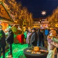 Weihnachtsmarkt Döbeln - Weihnachten in der Region Leipzig Der Weihnachtsmarkt in Döbeln zeigt eine stimmungsvolle Szenerie mit leuchtenden Lichtern und fröhlichen Menschen, die die festlich geschmückten Holzbuden erkunden. Die warme Beleuchtung und der Sternenhimmel schaffen eine einladende Atmosphäre, während Besucher in Winterkleidung zwischen den Ständen flanieren.