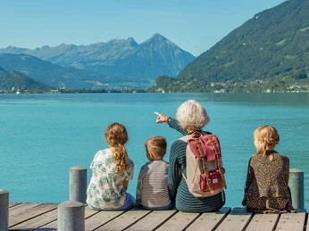 Grandmother sitting with children on the jetty in Iseltwald
