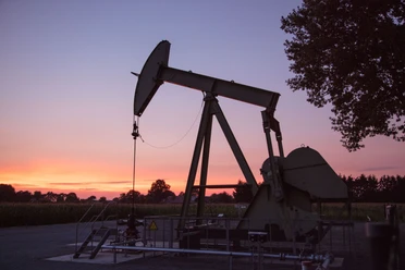 Ölnicker bei Sonnenuntergang im Rühlermoor Ölpumpe im Rühlermoor vor farbigem Abendhimmel, umgeben von Feldern und Bäumen bei Sonnenuntergang.
