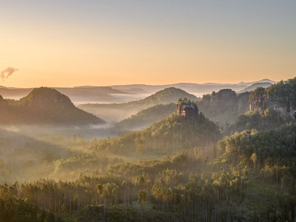Dageraad over met mist bedekte, beboste heuvels en rotsen.