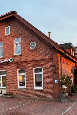 Zur Nordseite Backsteingebäude mit roten Dachziegeln, gepflastertem Hof und dem Schriftzug „Zur Nordseite“.