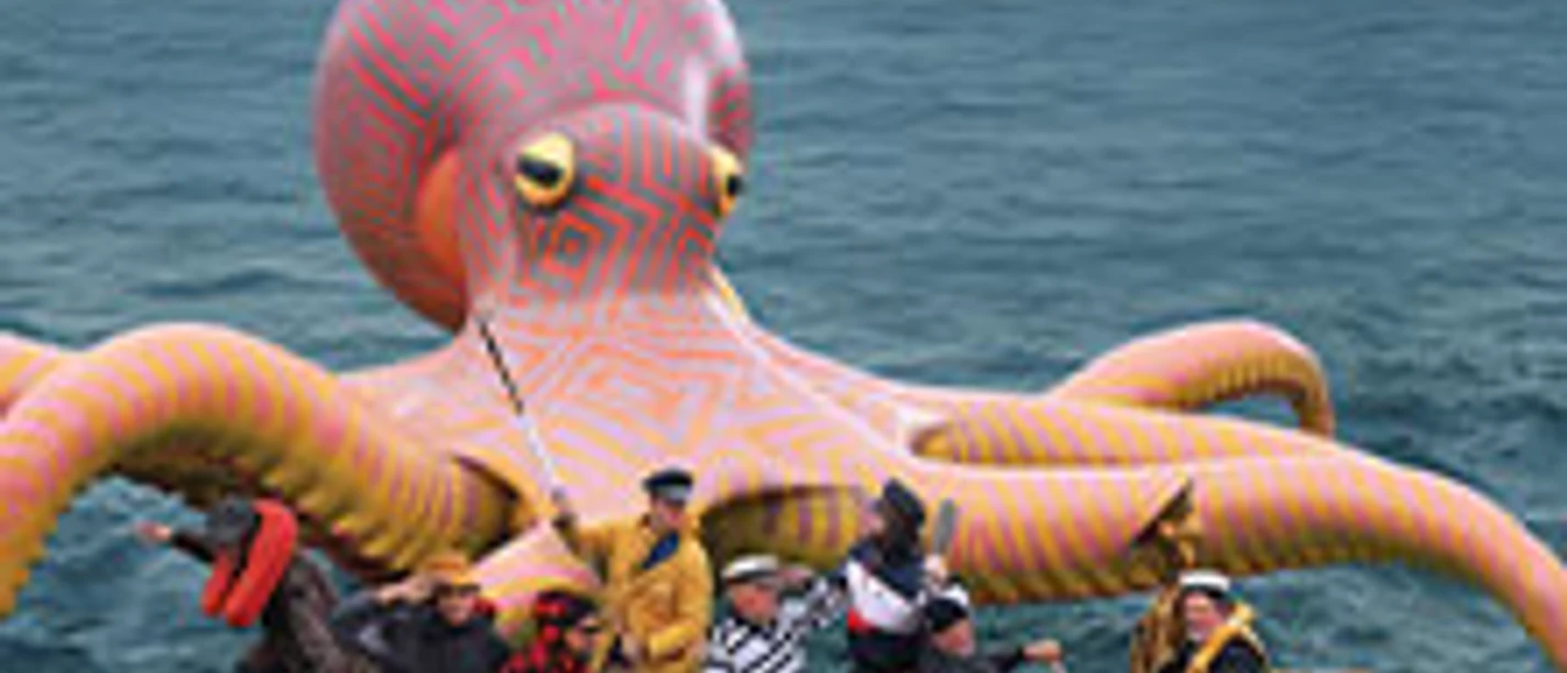Cover der "Fat Freddy's Drop" Tour: Bandmitglieder in Boot vor riesiger Oktopusskulptur.