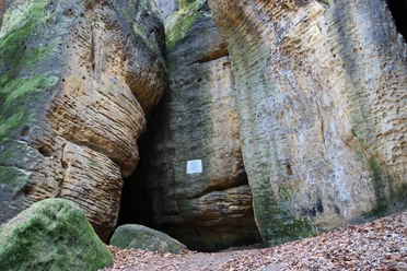Eingang Götzinger Höhle an den Bärensteinen Hohe Sandsteinfelsen umgeben einen schmalen Durchgang in einem Wald.