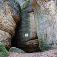 Eingang Götzinger Höhle an den Bärensteinen Hohe Sandsteinfelsen umgeben einen schmalen Durchgang in einem Wald.High sandstone cliffs surround a narrow passageway in a forest.Vysoké pískovcové skály obklopují úzký průchod v lese.Wysokie klify z piaskowca otaczają wąskie przejście w lesie.Hoge zandstenen kliffen omringen een smalle doorgang in een bos.Alte scogliere di arenaria circondano uno stretto passaggio in una foresta.