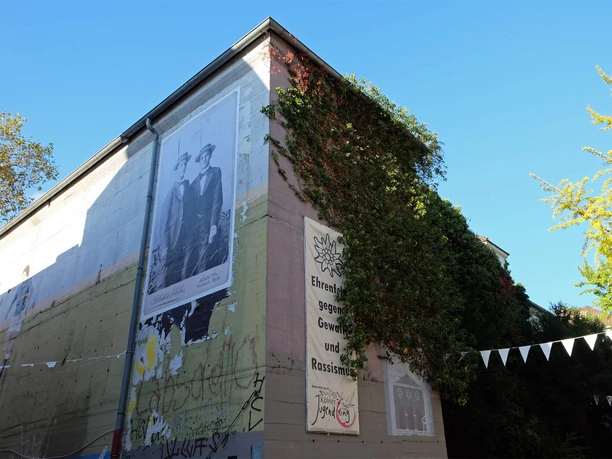 BunkerK101 Graffiti-verzierter Bunker mit großen Wandbildern und satt begrünten Ecken unter blauem Himmel.