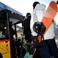 Personen mit Wintersportgeräten steigen in ein Postauto Bus ein