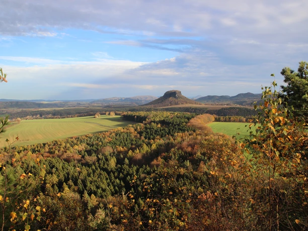 Autumn landscape with wooded hills and a striking mountain in the background.