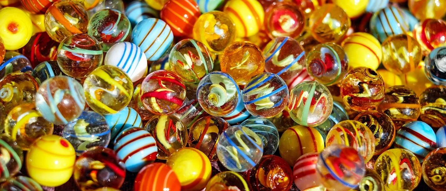 Murmeln Bunte Glasmurmeln in leuchtenden Farben liegen dicht beieinander und spiegeln das Sonnenlicht.